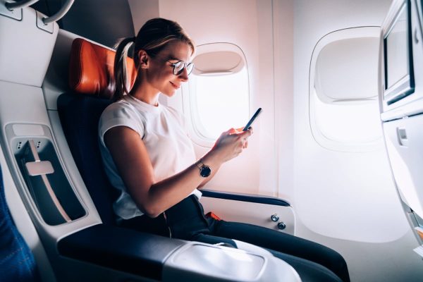 Woman on an airplane using Wifi on her phone